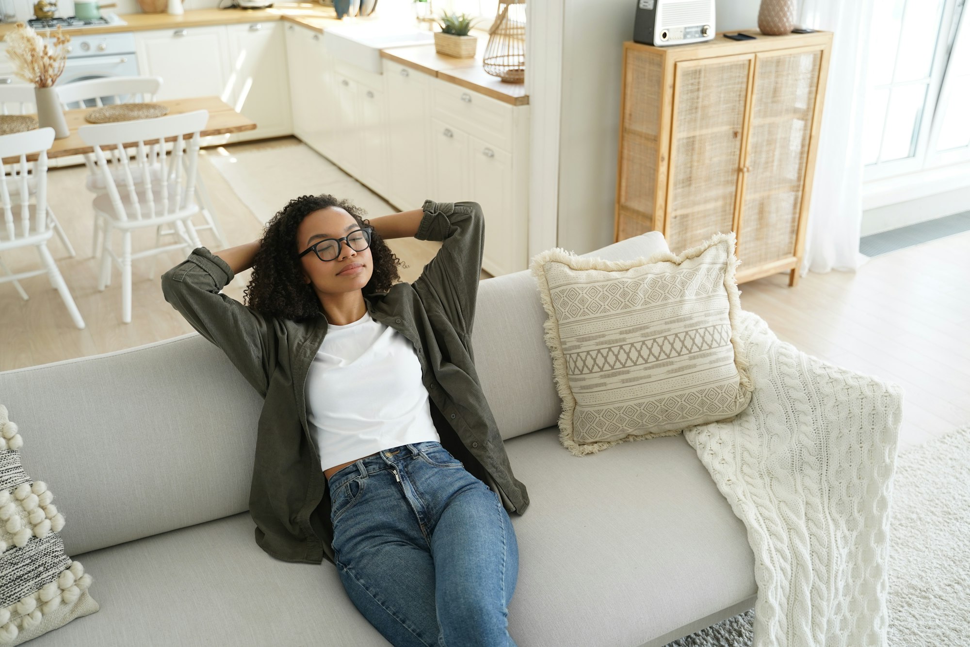 Calm african american girl enjoy fresh conditioned air, resting, sitting on cozy sofa in living room