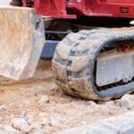 Caterpillar wheels of an excavator on rocks at a construction site.